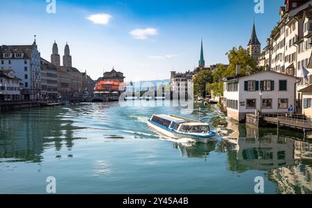 Ein Ausflugsboot fährt auf der Limmat mit den Zwillingstürmen von Grossmunster nach hinten im Zentrum von Zürich, Schweiz. Stockfoto