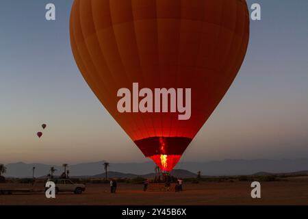 Inmitten der Erwartung des Abenteuers steht ein Heißluftballon bereit für den Start, während die Flammen zum Leben erwachen Stockfoto