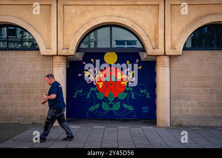 Ein Mann läuft an einem Kunstwerk des Weston Wallz Street Art Festivals im Badeort Weston-Super-Mare, Somerset, vorbei, wo es nur eines von 18 neuen Werken ist, die dieses Jahr zusammen mit 46 anderen Wandmalereien in der Stadt geschaffen wurden. Bilddatum: Montag, 16. September 2024. Stockfoto