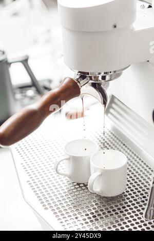 Der Detaillierte Espresso-Zubereitungsprozess Mit Frisch Gebrühtem Kaffee, Der In Zwei Weiße Tassen Von Professional Coffee Maker Tropft Stockfoto