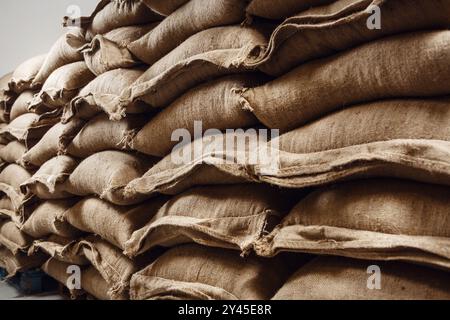 Jutebeutel gefüllt mit frischen grünen Kaffeebohnen, gestapelt in einem Lager, bereit für die Verarbeitung und Verteilung Stockfoto