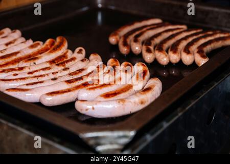 Auf dem Grill, gegrillte Würstchen, frisch gekochte Würstchen, Outdoor-Kochen, Grillparty, Grillmöglichkeiten im Sommer, Lebensmittelkonzept Stockfoto