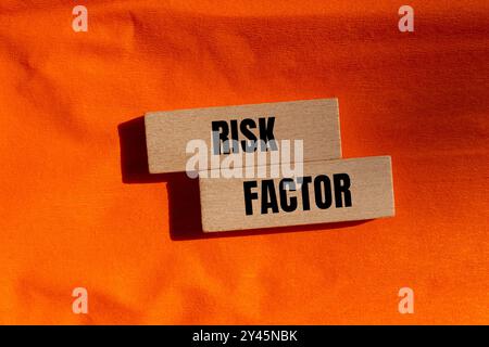 Risikofaktor-Meldung auf Holzblöcken mit orangefarbenem Hintergrund. Konzeptionelles Risikofaktorsymbol. Kopierbereich. Stockfoto