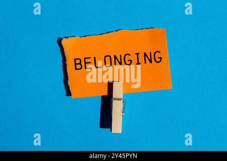 Zugehörige Nachricht auf gerissenem orangenem Papier auf blauem Hintergrund. Konzeptionelles Zugehörigkeitssymbol. Kopierbereich. Stockfoto