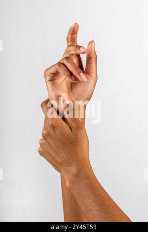 Anonyme afroamerikanische Frau mit perfekt gepflegten Nägeln, die Hände vor weißem Hintergrund streicheln Stockfoto