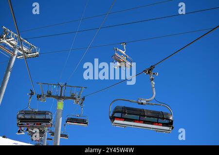 Sessellifte für Skifahrer und Snowboarder an einem klaren, sonnigen Tag in einem französischen Skigebiet Stockfoto