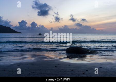 Beau Vallon Beach Landschaft mit nassem Küstensand und Silhouetten von Felsen bei Sonnenuntergang. Mahe Island, Seychellen Stockfoto