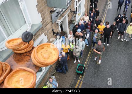 8. September 2024. Ramsbottom, Bury, Lancashire UK. Die Weltmeisterschaft Im Schwarzen Pudding-Werfen. Die Teilnehmer stehen auf einem „goldenen Gitter“, das feierlich auf die Bridge Street im Dorf Ramsbottom geführt und an der Tür des Oaks Public House platziert wird. Die Teilnehmer stehen mit einem Fuß auf der Startaufstellung, und mit einem „Lob“ unter den Armen schleudern 3 schwarze Puddings von Chadwicks of Bury auf 12 Yorkshire Puddings auf einem Sockel 30 Fuß/6 Meter hoch auf einem Gerüst. Der Sport steht für die Rivalität zwischen den benachbarten englischen Countys Lancashire und Yorkshire, die auf den Krieg zurückgeht Stockfoto