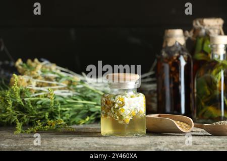 Verschiedene Tinkturen in Flaschen und Kräuter auf Holztisch Stockfoto