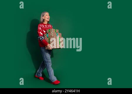 Foto der schönen schönen schönen Frau tragen trendigen Pullover Tragen Stapel Geschenk Spaziergang leerer Raum isoliert auf grünem Hintergrund Stockfoto