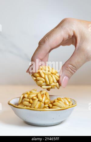 Panellets. Frau Hand hält typisch katalanische herbstliche süße Nachspeise auf weißem Marmor für den 1. November, Halloween und Kastanie mit Mandel- und Pinienkernen. Stockfoto