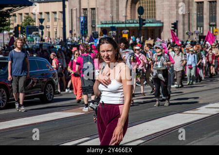 Eine Frau, die verwirrt mit den Demonstranten des Aussterbens der Rebellion Finnland im Hintergrund in Helsinki, Finnland, aussieht Stockfoto