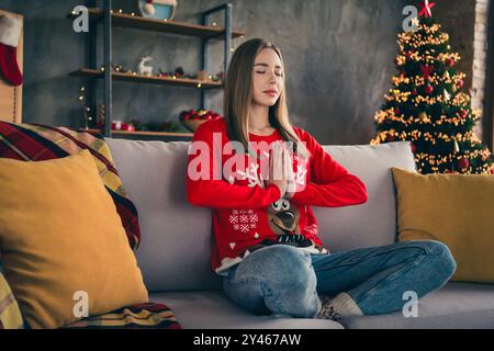 Großes Foto der attraktiven jungen Frau Sit Sofa meditativ gekleidet rot weihnachten Outfit gemütliches Tageslicht Haus Party Dekoration Innenraum Stockfoto