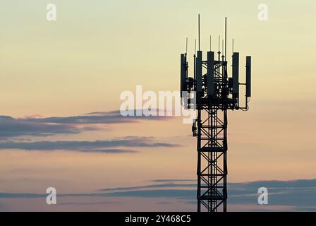 Telekommunikationsturm, Basisstation für Mobilfunknetz am farbenfrohen Himmel mit Wolken bei Sonnenuntergang. Silhouette. Mobilfunkantenne. Trencin, Slowakei Stockfoto