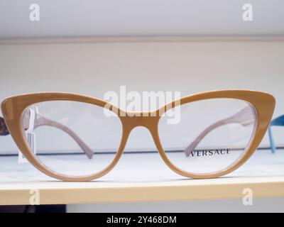 Beigefarbener Rahmen für Katzenaugen mit klaren Gläsern wird in einem Regal in einem Optikergeschäft ausgestellt Stockfoto