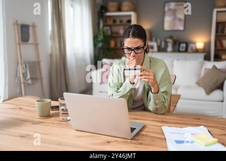 Verwirrte junge Frau, die Probleme mit blockierter Kreditkarte hat, die unsichere Online-Zahlung mit Laptop zu Hause abgelehnt hat, ungültiges abgelaufenes Konto, tr Stockfoto