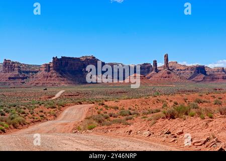 Die Schotterstraße schlängelt sich über den Boden des gesäumten Tals zwischen hohen Felsenformationen des Valley of the Gods in Utah Stockfoto