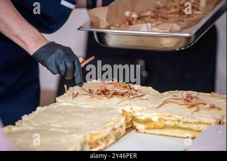 Eine Hand in einem schwarzen Handschuh ziert einen großen Rhabarberkuchen. Geringe Tiefe von feld Stockfoto