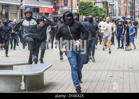 4. August 2024 Bolton, Lancashire, Vereinigtes Königreich. Nach dem gewaltsamen Tod junger Mädchen in Southport kam es in ganz Großbritannien zu gewalttätigen Auseinandersetzungen, die von rechtsextremen Gruppen angeheizt wurden, die im Internet rassistische und islamophobe Desinformationen verbreiten. In Bolton wurde eine Gruppe rechtsextremer Demonstranten von einer kleinen Gruppe von Gegenprotestierenden angegriffen, die von der Greater Manchester Police in Aufruhr auseinander geriet wurden. Irgendwann stürmte eine große Menge asiatischer Männer den Rathausplatz auf, um sich der Rechtsextremen zu stellen. Die beiden gegnerischen Gruppen verteilten sich dann auf die Stadt, getrennt von der Polizei. Zahlreiche Verhaftungen wegen gewalttätiger Unruhen waren m Stockfoto