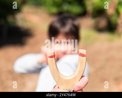 Kind, das im Freien eine Schleuder im Fokus hat Stockfoto