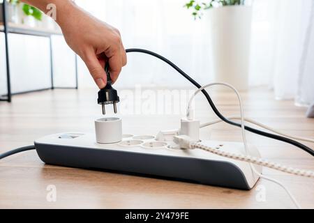 Mann, der den Netzstecker einsteckt. Steckdose zu Hause. Stockfoto