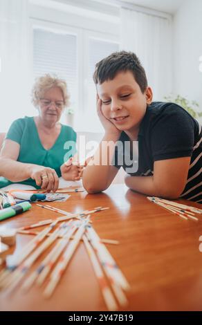 Großmutter und Enkel spielen fröhlich zusammen ein Pick-up-Stick-Spiel Stockfoto