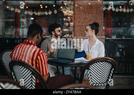 Geschäftstreffen in einem Café mit Kollegen, die Diagramme und Daten auf Laptops diskutieren. Stockfoto