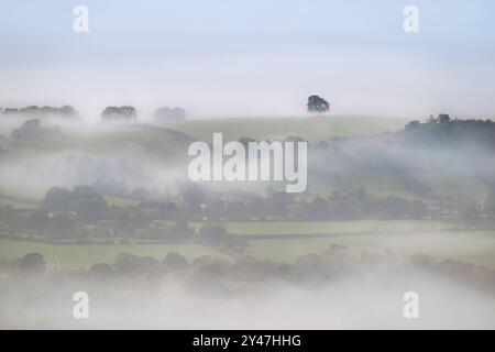 Ein starker Morgennebel auf den Somerset Levels, wie von Deer LEAP, Mendip Hills, Somerset, Großbritannien, zu sehen, mit Bäumen, die gerade erst durchbrechen Stockfoto