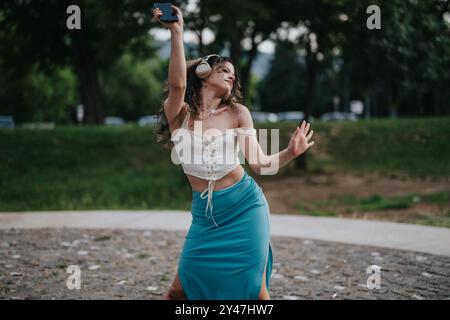 Fröhliche junge Frau tanzt frei draußen mit Kopfhörern Stockfoto