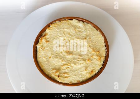 Veganer Käsekuchen Close up auf weißem Holztisch. Draufsicht auf ganzen runden Käsekuchen in brauner Platte auf hellem Hintergrund. Hausgemachte Küche, Käsecremekuchen. Hochwertige Fotos Stockfoto