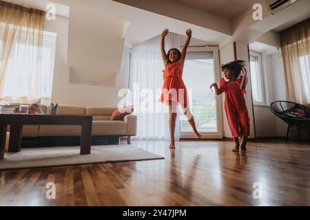 Fröhliche Schwestern tanzen zusammen in einem hellen, modernen Wohnzimmer Stockfoto