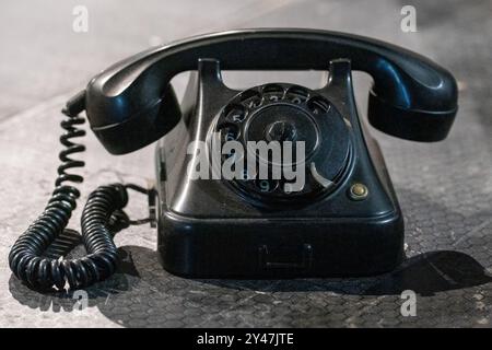 Schwarzes Retro-Telefon am Boden: Wählen Sie meine Nummer, Weckrufkonzept. Stockfoto