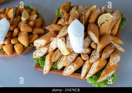 In Scheiben geschnittene Rührkäse oder Knödel mit pikanter Käse- und Schinken-Füllung, mit Salat und Zitronenscheiben als Dekoration. Serviert auf weißem Tischtuch Stockfoto