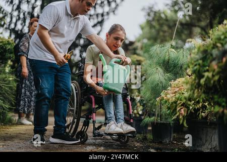 Der Mann hilft der Frau im Rollstuhl, die Pflanzen im Garten bewässert Stockfoto