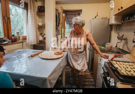 Ältere Frau, die hausgemachtes Gebäck in gemütlicher Küche backt Stockfoto