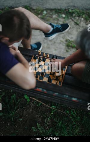 Zwei Personen, die auf einer Bank an einem intensiven Freiluftschachspiel teilnehmen Stockfoto