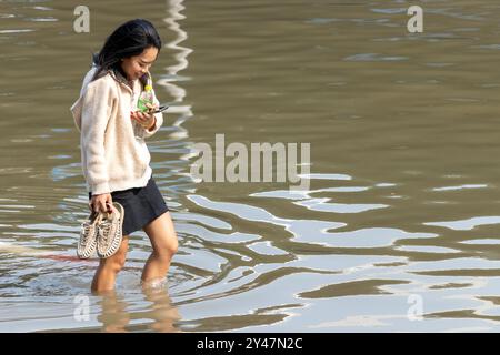 SAMUT PRAKAN, THAILAND, Februar 2024, Eine Frau waten durch eine überflutete Straße Stockfoto