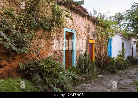 Paraty, Brasilien. Fire Street. Steinstraße mit mehreren blühenden Bäumen. Häuser mit bunten Türen und Fenstern aus der Kolonialzeit. Stockfoto