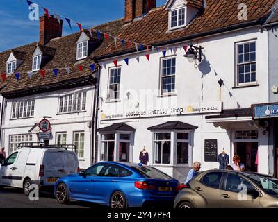 Bunting schloss sich dem Mercy in Action Boutique Charity Shop mit Freiwilligen an und parkte Autos in Highworth, Wiltshire, England Stockfoto