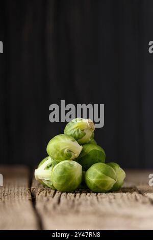 Ein Haufen frischer Rosenkohl auf hölzernem Hintergrund. Veganismus, gesundes grünes Gemüse, Entgiftung. Stockfoto