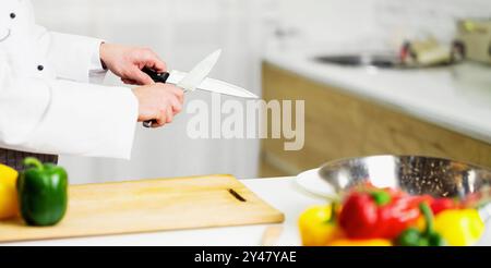 Nicht erkennbare Koch Mann Schärfen von Messern arbeiten In Küche Indoor, 7/8 Stockfoto