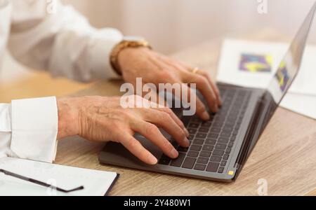 Nahaufnahme der Hände eines Seniorenmannes, die auf Laptop schreiben, Cropped Stockfoto