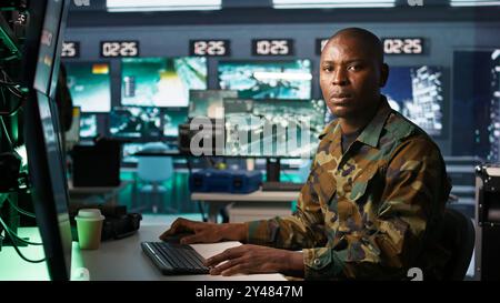 Porträt eines Militäragenten, der im Kontrollraum arbeitet und Aufklärungsdaten analysiert. Ein Agent des Geheimdienstes kontrolliert Drohnen, die strategische Ziele angreifen, Kamera B Stockfoto