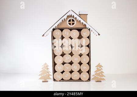 Papercraft Adventskalender aus recyceltem Papier, ein Papphaus mit einem Weihnachtsbaum daneben, Countdown, Nahaufnahme Produktfoto, rund Stockfoto