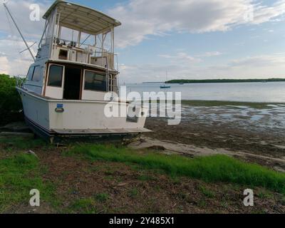 Weite Aussicht auf Ebbe-Pfützen in Richtung angespülltes, großes weißes Fischerboot am Maximo Park Water in Richtung Skyway Channel Stockfoto