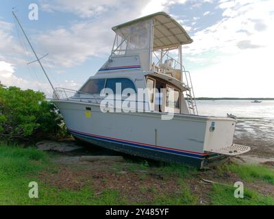 Weite Aussicht auf Ebbe-Pfützen in Richtung angespülltes, großes weißes Fischerboot am Maximo Park Water in Richtung Skyway Channel Stockfoto