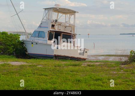 Weite Aussicht auf Ebbe-Pfützen in Richtung angespülltes, großes weißes Fischerboot am Maximo Park Water in Richtung Skyway Channel Stockfoto