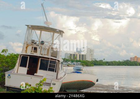 Weite Aussicht auf Ebbe-Pfützen in Richtung angespülltes, großes weißes Fischerboot am Maximo Park Water in Richtung Skyway Channel Stockfoto