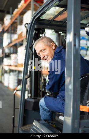 Ein älterer Arbeiter arbeitet am Lader im Lager Stockfoto