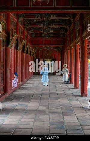 Frauen in traditioneller Kleidung in einer langen Galerie in der Zitadelle, Hue, Vietnam Stockfoto